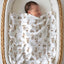Newborn asleep under a farm animal name blanket in a bassinet