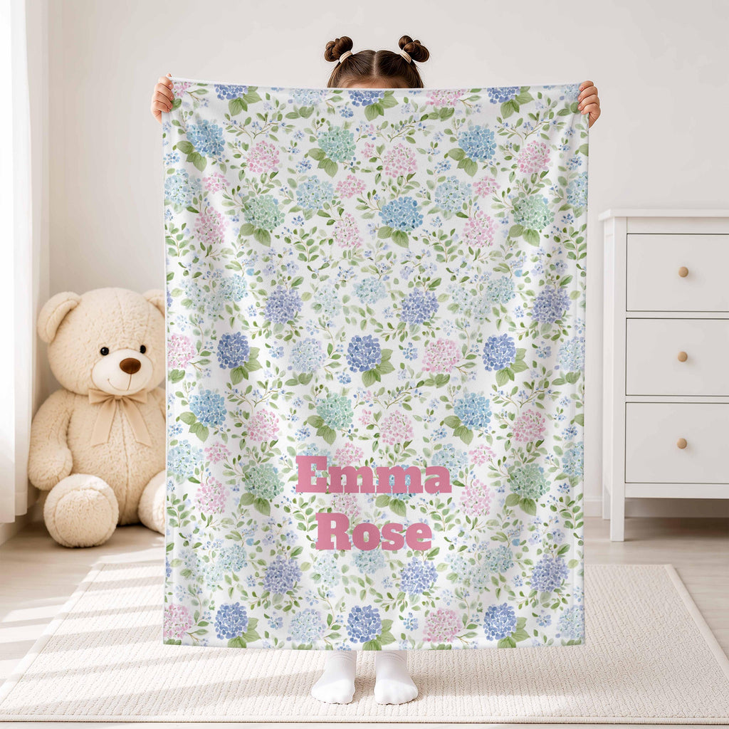 Child holding a pink and blue hydrangea blanket with Emma Rose