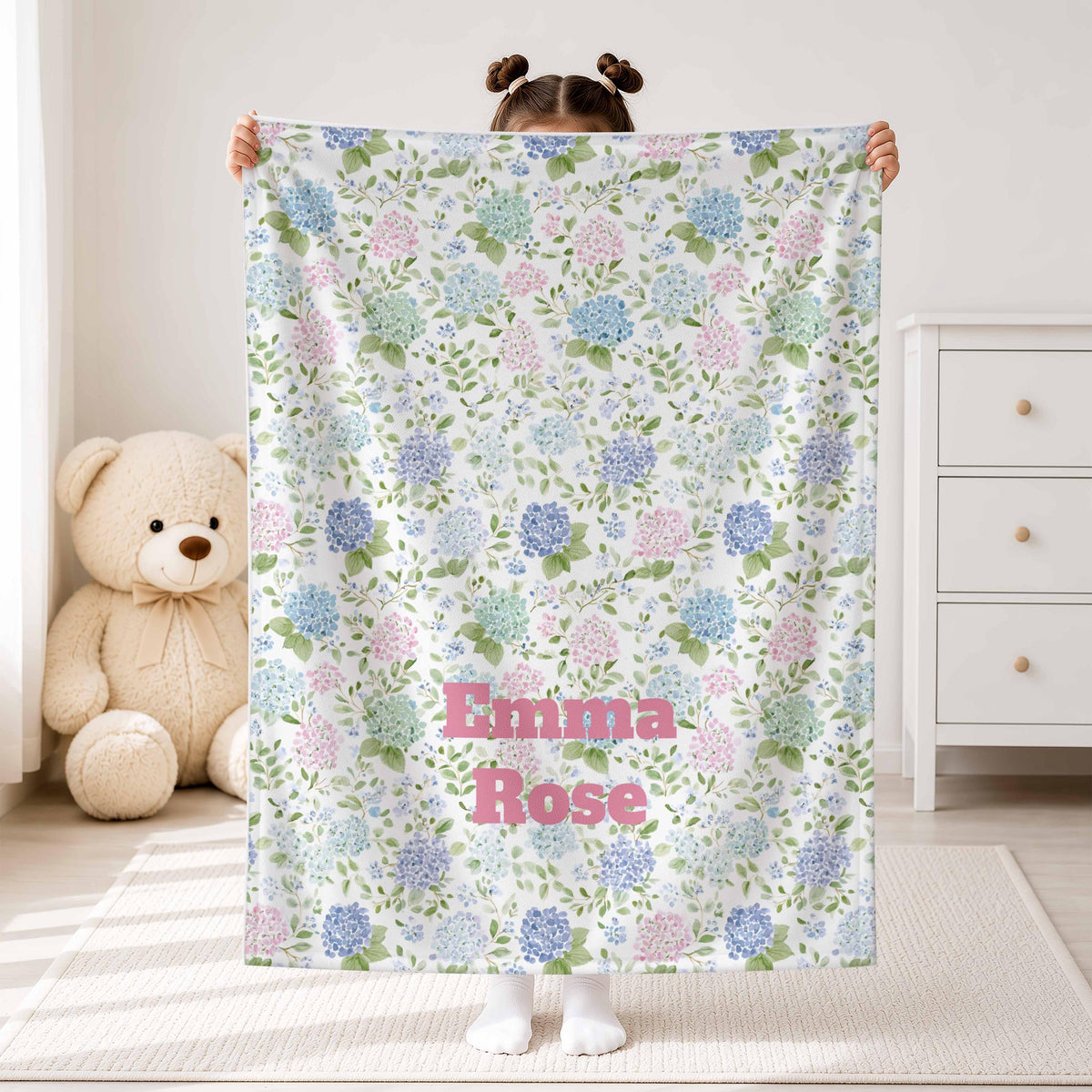 Child holding a pink and blue hydrangea blanket with Emma Rose